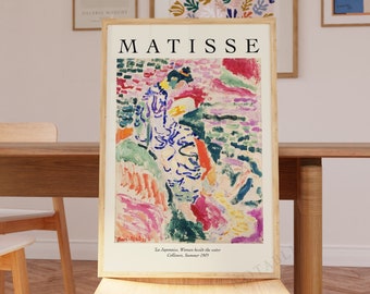 May include: A set of four framed art prints featuring colorful abstract paintings by Henri Matisse. The prints are hung on a white wall above a wooden table and chairs. The prints are titled "Matisse" and feature the artist's signature.