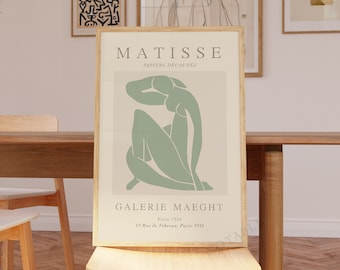 May include: A framed art print featuring a green abstract figure with the text "MATISSE PAPIERS DECOUPES GALERIE MAECHT Paris 1954 13 Rue de Téhéran, Paris VIII"