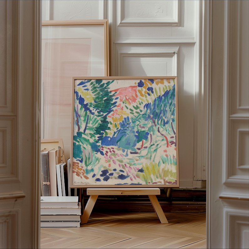 May include: A framed abstract painting with a colorful landscape scene featuring shades of blue, green, pink, and yellow. The painting is on a wooden easel.