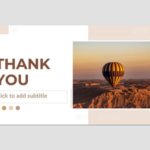 May include: A hot air balloon with yellow, blue, and black stripes floats over a desert landscape at sunset. The sky is a soft orange and pink. The text "THANK YOU" is in brown letters on a white background. The text "Click to add subtitle" is below the text "THANK YOU".