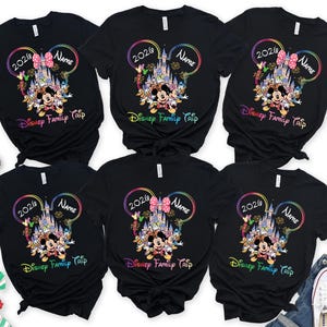 May include: Black t-shirts featuring a Disney design with Mickey and Minnie Mouse, a castle, and the text "2020", "Name", and "Disney Family Trip". The design is framed by a rainbow-coloured Mickey Mouse ear outline.