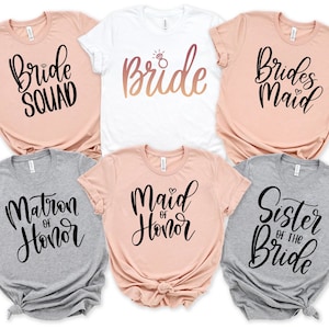 May include: Six t-shirts with different text printed on them. The shirts are in various colors, including peach, white, and gray. The text on the shirts includes "Bride Squad", "Bride", "Bridesmaid", "Matron of Honor", "Maid of Honor", and "Sister of the Bride".