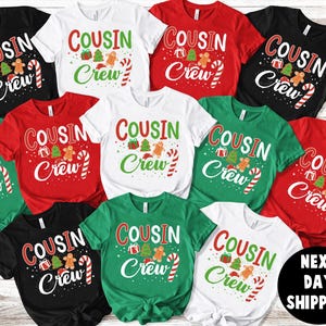 May include: A collection of Christmas-themed t-shirts in various colors, including black, white, red, and green. Each shirt features the text "COUSIN Crew" with festive graphics like gifts, trees, gingerbread men, and candy canes. The shirts are short-sleeved.