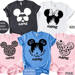 Puede incluir: Cinco camisetas en varios colores: gris oscuro, blanco, azul claro y rosa. Cada camiseta presenta un dise&ntilde;o de silueta de Mickey Mouse con la palabra "NAME" impresa debajo. Los dise&ntilde;os incluyen gafas de sol, un lazo, corazones y un castillo.