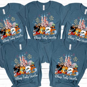 Peut inclure: Cinq t-shirts bleus avec un graphisme color&eacute; repr&eacute;sentant des personnages Disney, un ch&acirc;teau et le texte "2023 Disney Family Vacation". Le motif comprend Mickey Mouse, Donald Duck et Dingo.