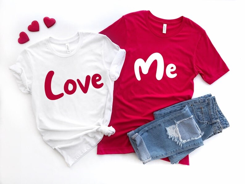 Puede incluir: Dos camisetas blancas con texto rojo. Una camiseta dice "Love" y la otra dice "Me".