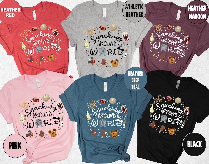 May include: Several short-sleeved t-shirts in shades like red, grey, and black. Each shirt displays the phrase "Snacking Around the World" in a circular design, accompanied by food and character illustrations. The shirts are available in multiple colours.
