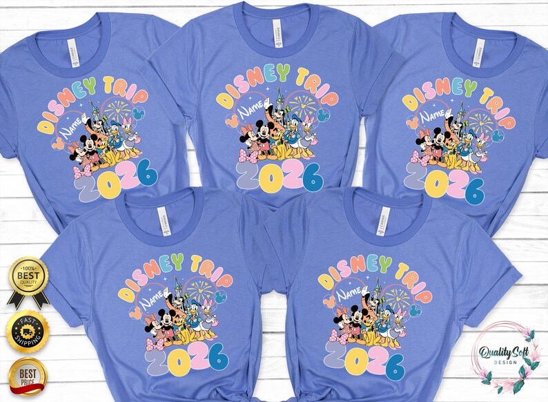 K&ouml;nnte beinhalten: Mehrere hellblaue T-Shirts mit einem farbenfrohen Disney Trip-Design. Das Design zeigt Micky und Minnie Maus, Donald und Daisy Duck sowie den Text "Disney Trip Name 2026".