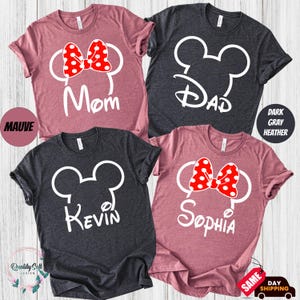 four t-shirts with the same design, featuring the names Kevin and Sophia along with the iconic Mickey Mouse ears. The t-shirts are in various colors, including pink, black, and gray.