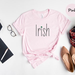 May include: Pink t-shirt with the word "Irish" and a shamrock printed on the front.