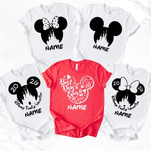 Puede incluir: Seis camisetas con dise&ntilde;os de Disney. Cinco son blancas, con siluetas negras de Mickey Mouse con gr&aacute;ficos de castillo y la palabra "NAME". La camiseta roja dice "Best Day Ever" en un contorno de Mickey Mouse.