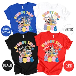K&ouml;nnte beinhalten: Vier kurz&auml;rmelige T-Shirts in K&ouml;nigsblau, Wei&szlig;, Schwarz und Rot. Jedes Shirt zeigt ein farbenfrohes "Disney Trip"-Design mit Zeichentrickfiguren, dem Jahr "2026" und anpassbarem Text. Die Shirts sind mit ihren jeweiligen Farben gekennzeichnet.