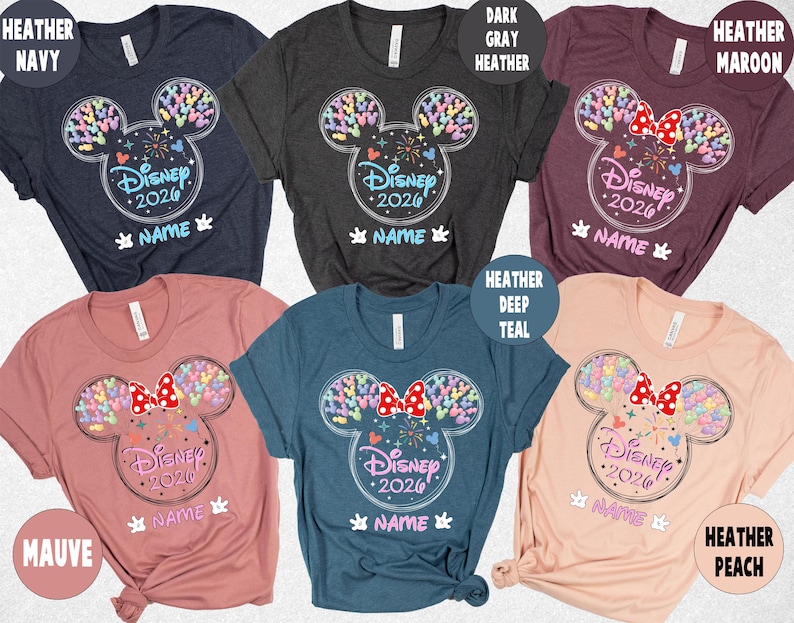 a collection of Disney-themed t-shirts in various colors, including navy, dark gray, maroon, peach, and teal. The t-shirts feature the iconic Mickey Mouse ears and the text "Disney 2020" along with the names "HEATHER" and "MAVE" printed on them.