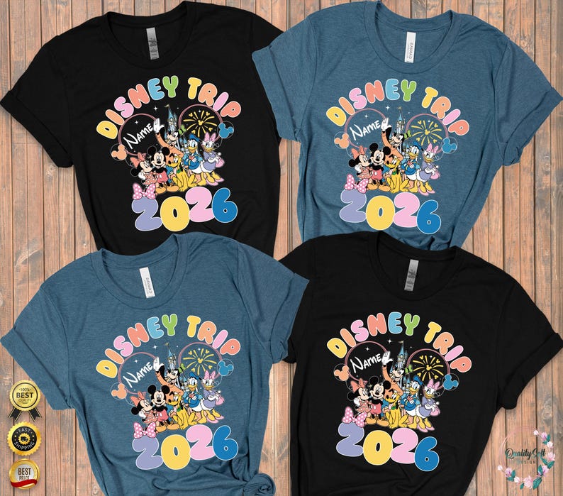 K&ouml;nnte beinhalten: Vier kurz&auml;rmelige T-Shirts in Schwarz und Blau, jedes mit einem farbenfrohen "Disney Trip"-Design mit Mickey Mouse, Minnie Mouse, Donald Duck und anderen Charakteren. Das Jahr "2026" ist deutlich sichtbar.