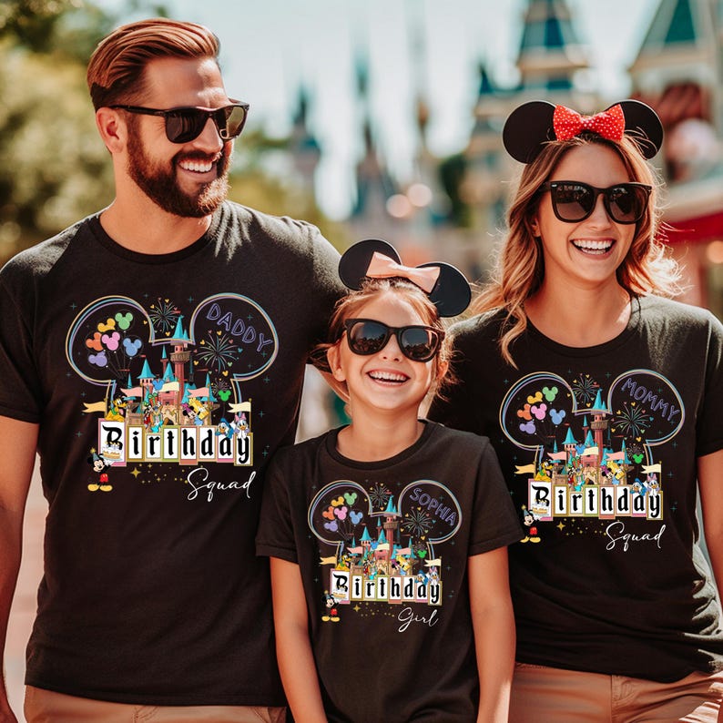 May include: Three people wearing black t-shirts with a colorful graphic design. The design includes a castle, balloons, and the words "Birthday Squad" and "Daddy", "Mommy", and "Girl". The shirts are for a family celebrating a birthday.