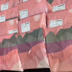 a collection of pink and gray packages or bags arranged in rows, with some of them labeled with shipping labels.