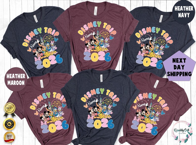 K&ouml;nnte beinhalten: Mehrere Shirts in Heather Navy, Heather Maroon und Dunkelblau. Jedes Shirt zeigt ein farbenfrohes "Disney Trip 2026"-Design mit Mickey Mouse, Minnie Mouse und anderen Disney-Figuren. Rundhalsausschnitt.