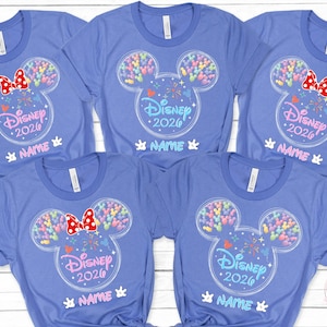 A collection of five blue t-shirts with Disney-themed designs, including Mickey Mouse ears and colorful balloons. The shirts have the text "Disney 2020" and "NAME" printed on them, suggesting they are personalized t-shirts for Disney guests.