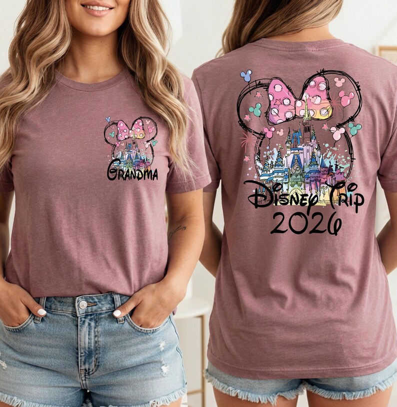 May include: Mauve t-shirt featuring a Minnie Mouse bow design with a castle and the text "Disney Trip 2020" on the back. The front of the shirt has a smaller Minnie Mouse bow design and the word "Grandma".