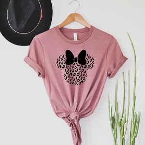 May include: A pink t-shirt with a black leopard print Minnie Mouse head design.