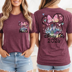 May include: Maroon t-shirt with a Minnie Mouse bow and castle graphic. The front of the shirt says "Auntie" and the back says "Disney Trip 2026". The design includes colorful accents and butterflies.