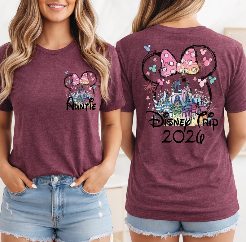 May include: Maroon t-shirt with a Minnie Mouse bow and castle graphic. The front of the shirt says "Auntie" and the back says "Disney Trip 2026". The design includes colorful accents and butterflies.