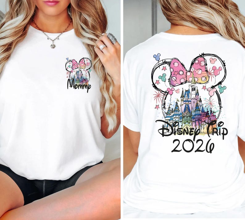 May include: White t-shirt featuring a colorful Minnie Mouse design with a castle and fireworks. The front of the shirt has the word "Mommy" in script. The back of the shirt says "Disney Trip 2026".