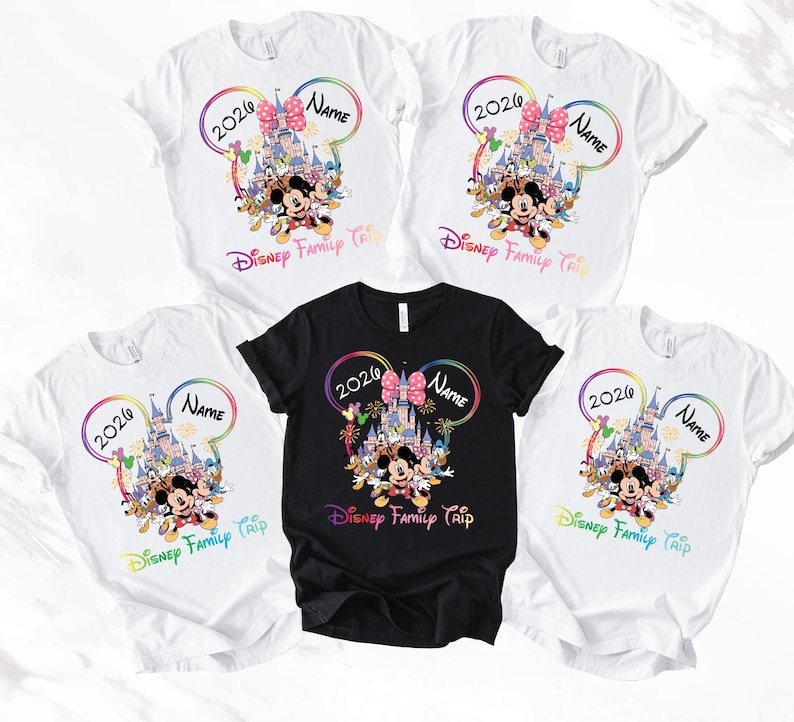May include: Five white and one black t-shirts with a Disney theme. Each shirt features a colourful design with Mickey Mouse, a castle, and the text "2026 Name Disney Family Trip". The design is framed by a rainbow-coloured outline.