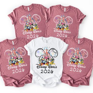 May include: Five t-shirts, four in mauve and one in white, featuring a Disney World 2026 design. The design includes a castle, Disney characters, and the names "Daddy", "Mommy", "Grandpa", and "Sophia".