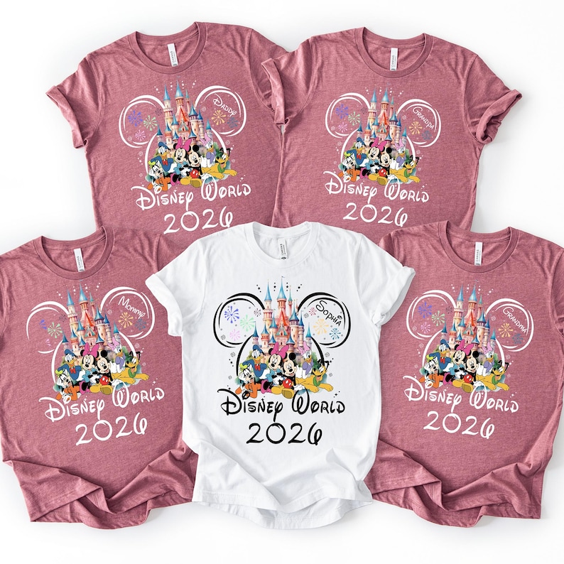 May include: Five t-shirts, four in mauve and one in white, featuring a Disney World 2026 design. The design includes a castle, Disney characters, and the names "Daddy", "Mommy", "Grandpa", and "Sophia".