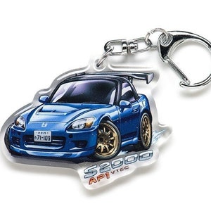 Puede incluir: Un llavero azul Honda S2000 con un anillo de llave plateado. El coche tiene un alerón negro y una matrícula que dice "5-71-103". El texto "S2000 AP1 VTEC" está impreso debajo del coche.