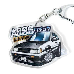 Op de afbeelding: Een witte en zwarte auto sleutelhanger met de tekst "AE86 Levin ハチロク" erop. De sleutelhanger is gemaakt van helder acryl en heeft een zilveren metalen ring.