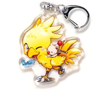 May include: A yellow and white cartoon character keychain with a small white character on its back. The larger character has a yellow beak and a red cherry on its tail. The keychain is made of clear acrylic and has a silver metal ring.