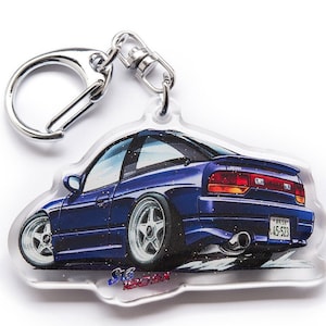 Op de afbeelding: Een blauwe Nissan 240SX sleutelhanger met een zilveren sleutelring. De auto is afgebeeld in een cartoon-stijl met een wit kenteken dat "45-523" aangeeft.