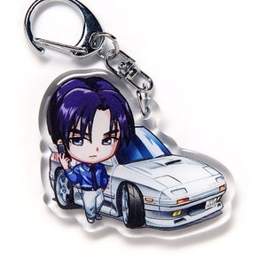 May include: Clear acrylic keychain featuring an anime-style character with purple hair, wearing a blue jacket and white trousers, leaning against a white sports car. The keychain has a silver clasp.