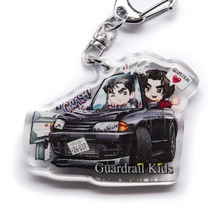 Op de afbeelding: Een zwart-witte anime-sleutelhanger met twee personages in een zwarte auto met de tekst "CRASH!" en "Guardrail Kids". De auto heeft een kentekenplaat met de tekst "#03-33* 26-037".