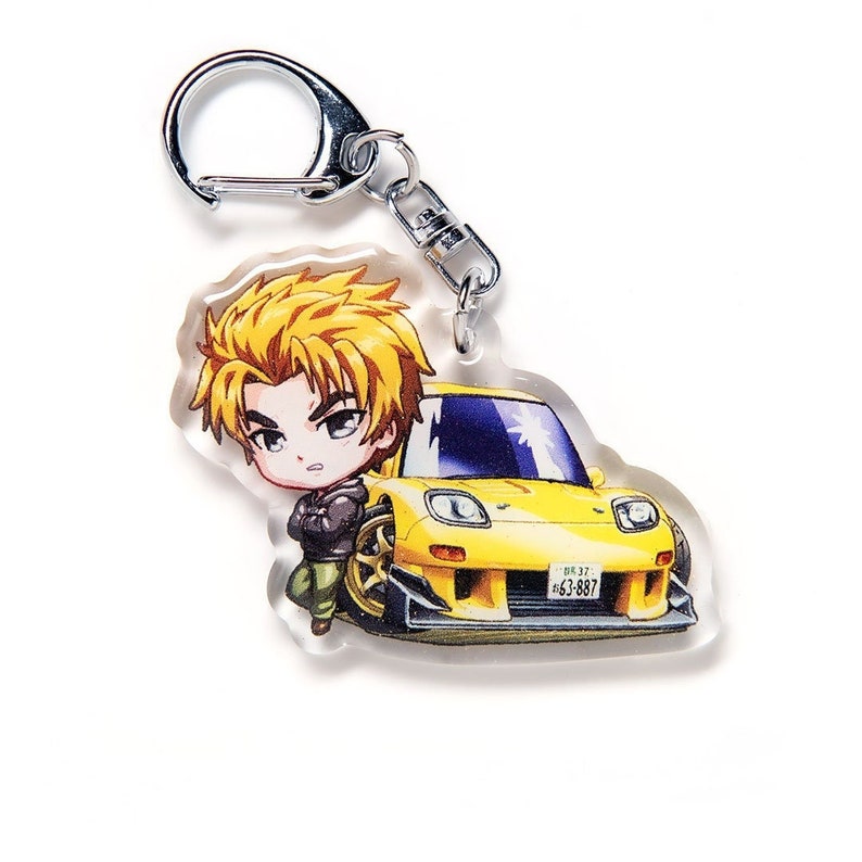 May include: A yellow and black anime character keychain featuring a cartoon man with blonde hair and a yellow car with a black spoiler and a license plate that reads "63-887".