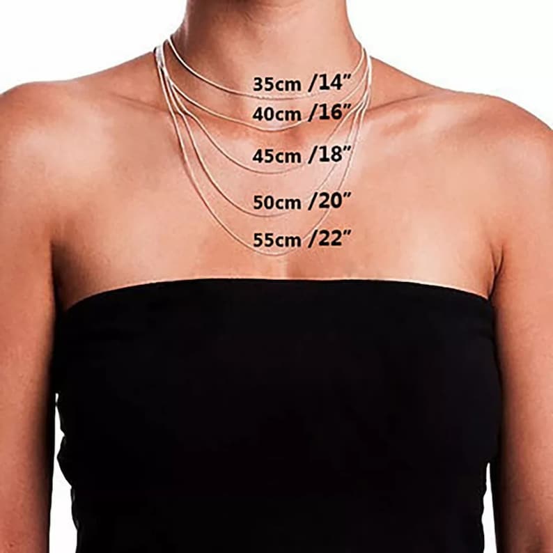 Puede incluir: Una persona con un top negro sin tirantes muestra una colecci&oacute;n de delicados collares plateados. Los collares var&iacute;an en longitud, con medidas de 35 cm (14"), 40 cm (16"), 45 cm (18"), 50 cm (20"), y 55 cm (22").