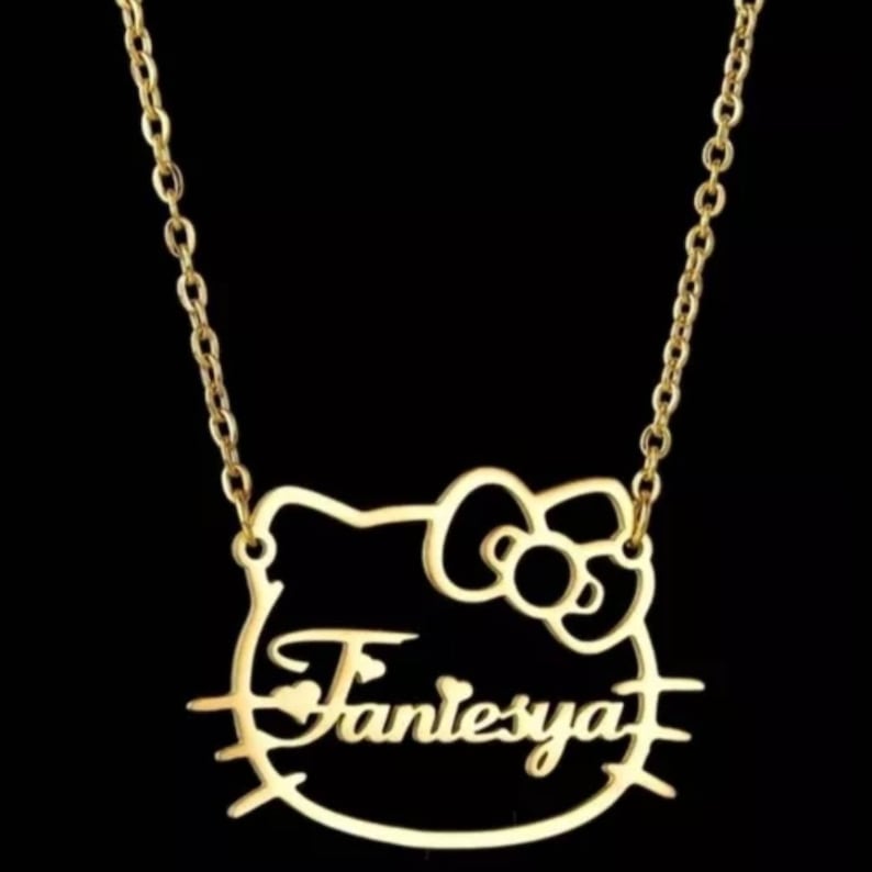May include: Gold-tone necklace with a Hello Kitty-shaped pendant featuring the name "Fantessya" inside.