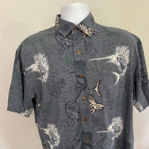 May include: A gray short-sleeved button-down shirt with a white and brown skeleton marlin fish print.