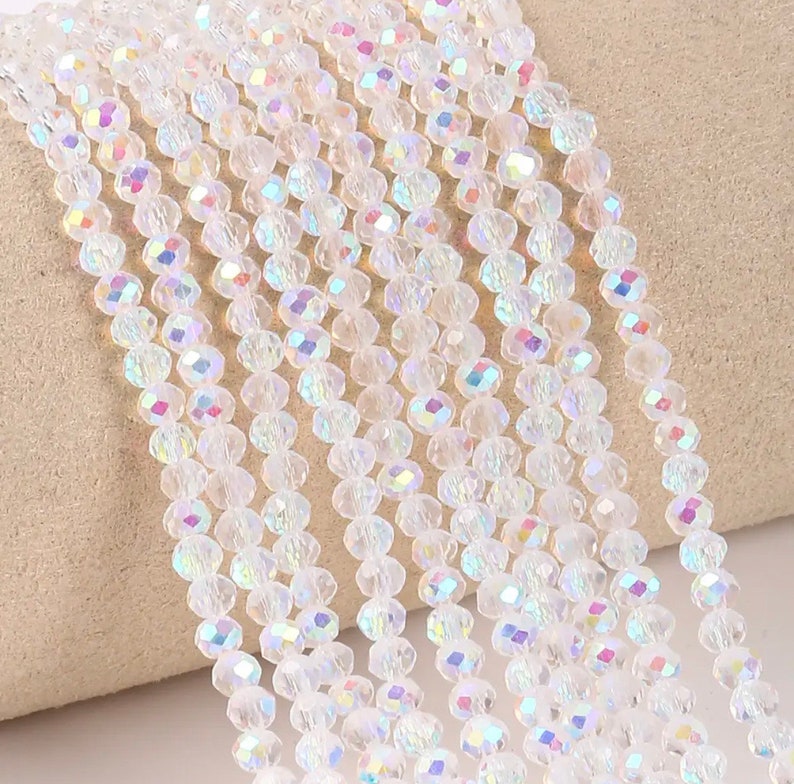 May include: A strand of clear iridescent glass beads. The beads are faceted and have a slight rainbow effect.