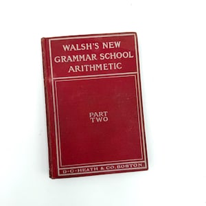 May include: A red hardcover textbook titled Walsh's New Grammar School Arithmetic Part Two, published by D.C. Heath & Co. Boston. The front cover features white text and a white rectangular border design on a solid red background with a worn spine.