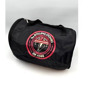 May include: A white ceramic mug with a black handle and the text "But First, Coffee" in a bold, black font. The mug is set against a blurred background, suggesting a cozy setting.