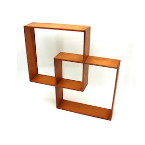 May include: A wooden wall shelf with a geometric design. The shelf is made of rectangular wooden frames in a warm brown color. The frames are arranged in an overlapping pattern, creating a modern and unique storage solution.