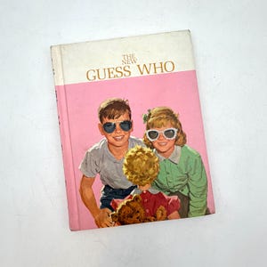 May include: A vintage book titled "The New Guess Who" with a pink cover. The cover features a smiling boy and girl wearing sunglasses, holding a doll and teddy bear. The book has a retro design.