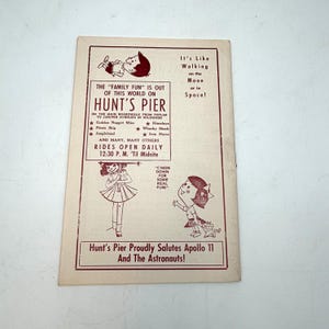 May include: Vintage Hunt's Pier advertisement with maroon text and illustrations. The text promotes rides and attractions, including Jungleland and the Pirate Ship. The ad also salutes Apollo 11 and the astronauts. The background is off-white.