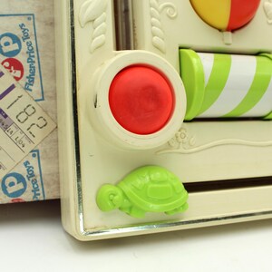 May include: A vintage Fisher-Price toy with a red button, a green and white striped roller, a green turtle, and a yellow and red ball. The toy is made of plastic and has a white background.
