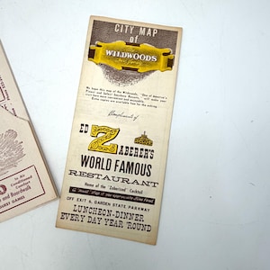 May include: Vintage city map of Wildwoods, New Jersey, with a gold and brown color scheme. The map features the text "City Map of Wildwoods" and "Ed Zaberer's World Famous Restaurant". The map is a vintage travel souvenir.