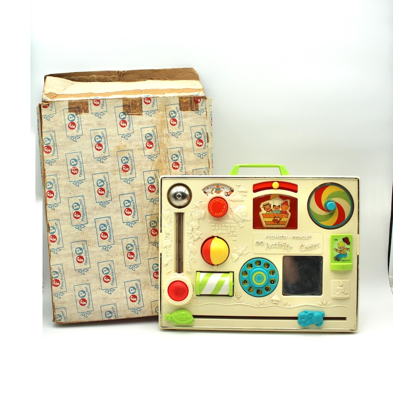 May include: A vintage Fisher-Price 60 Activity Center toy with a white base and colorful features, including a spinning wheel, a mirror, a phone dial, and a sliding bead bar. The toy is in its original box.