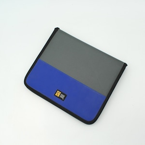 May include: A gray and blue Case Logic zippered binder. The top half is gray, and the bottom half is blue. The binder has a black border and a small Case Logic logo on the bottom right corner.